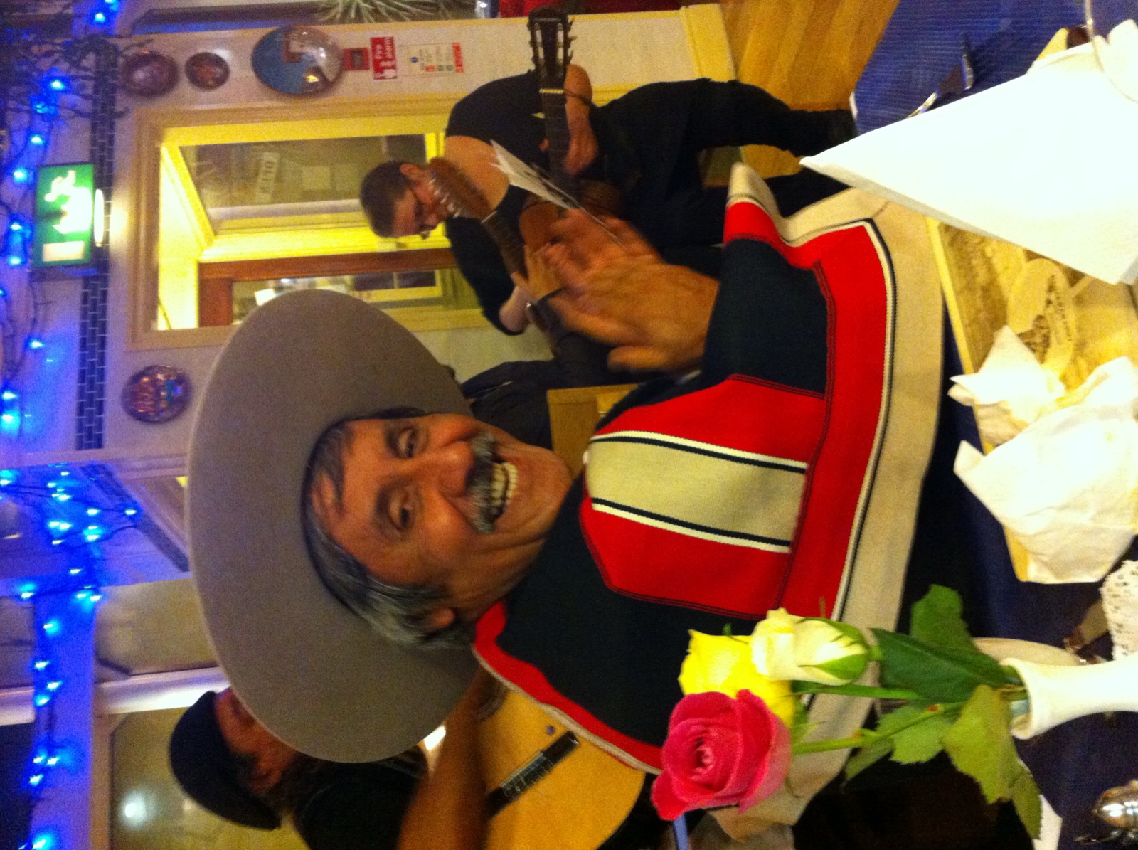 Chris's father wearing a sombrero, laughing, with mariachi guitarists behind him